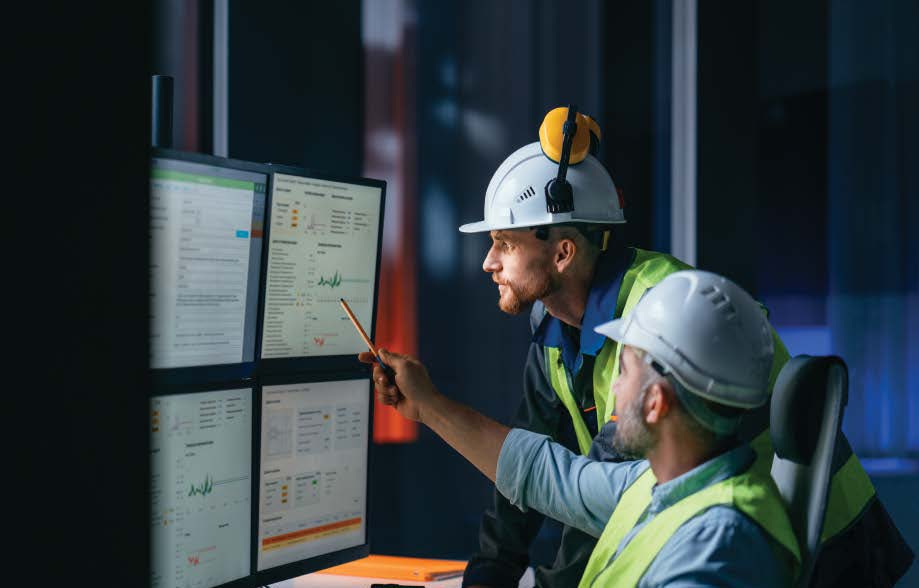 Plant floor workers looking at computer screens with data